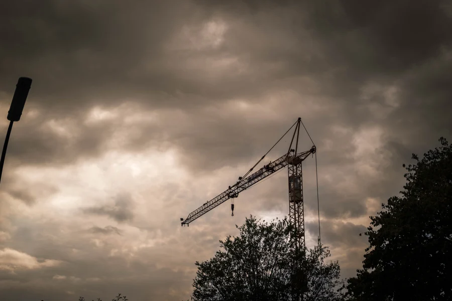 Silhouette eines Baukrans unter dunklen, leuchtenden Wolken