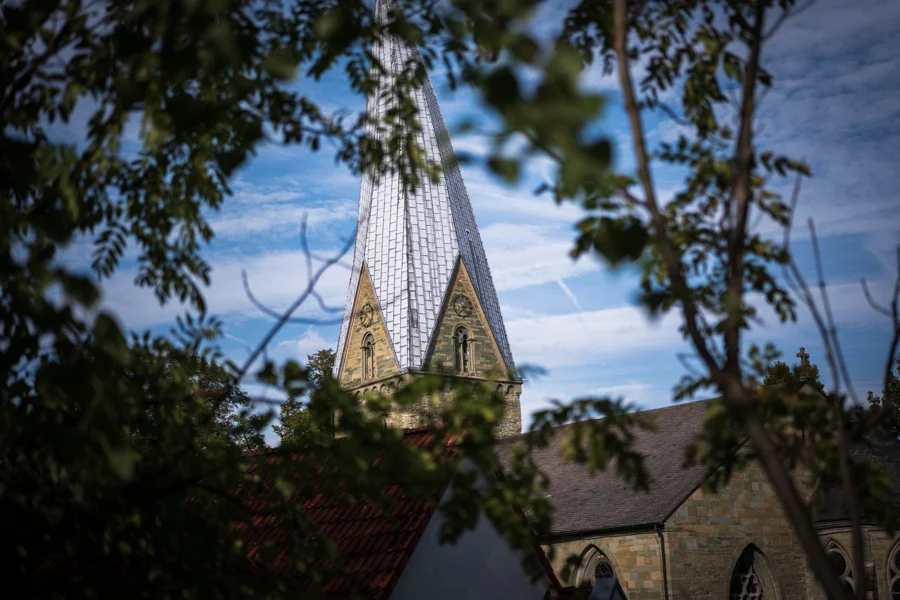 Ein Kirchturm eingerahmt von grünen Zweigen