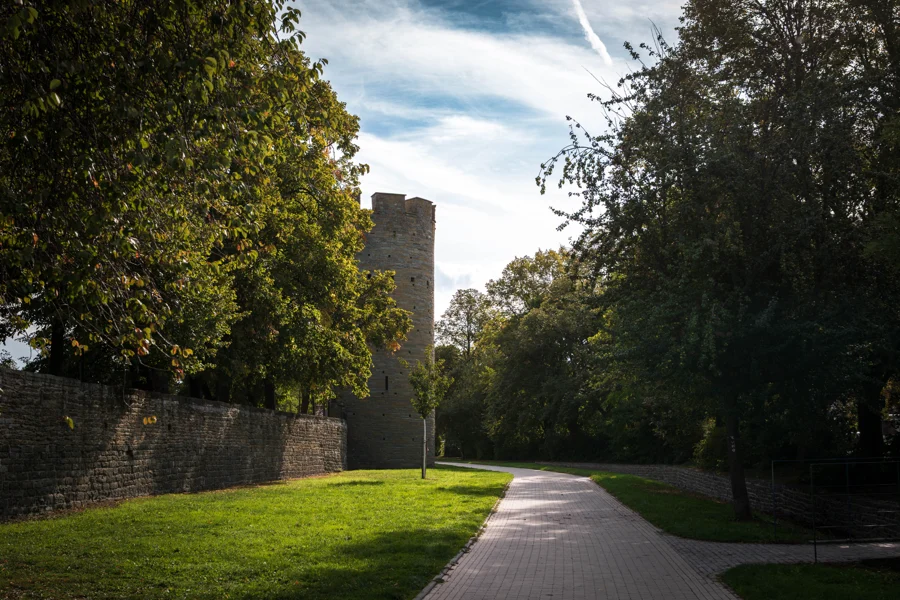 Ein Weg entlang einer alten Steinmauer und eines Turms im Grünen
