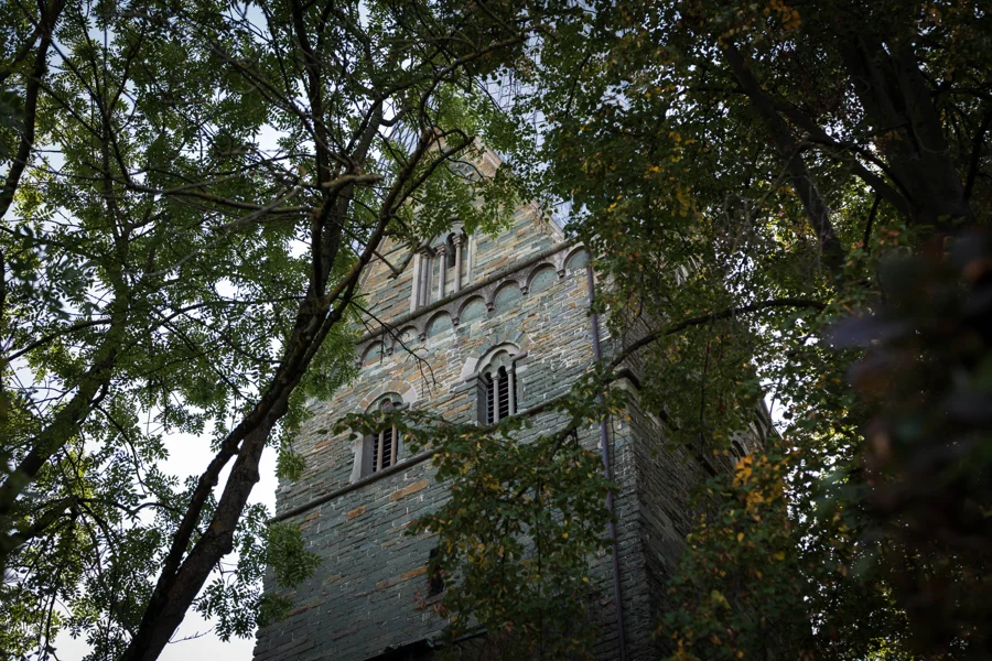 Ein alter steinerner Turm hinter grünen Baumzweigen