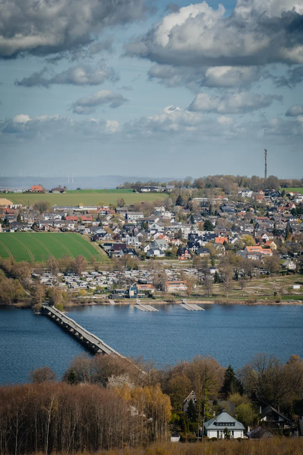 Hochformatiger Blick auf einen See und eine Stadt unter blauem Wolkenhimmel