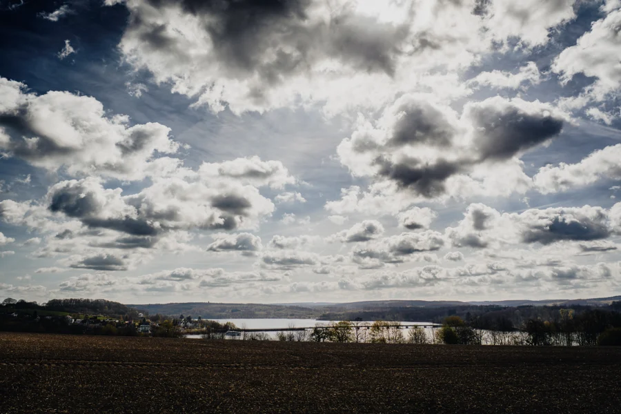 Dramatische Wolken und Sonnenlicht über einer Wasserfläche