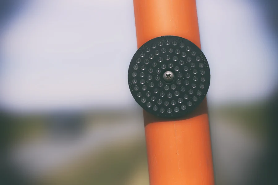 Nahaufnahme eines runden schwarzen Lautsprechergitters an einer orangefarbenen Fläche