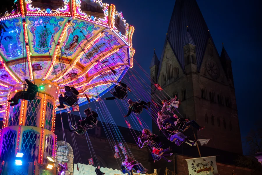 Beleuchtetes Kettenkarussell vor einer Soester Kirche