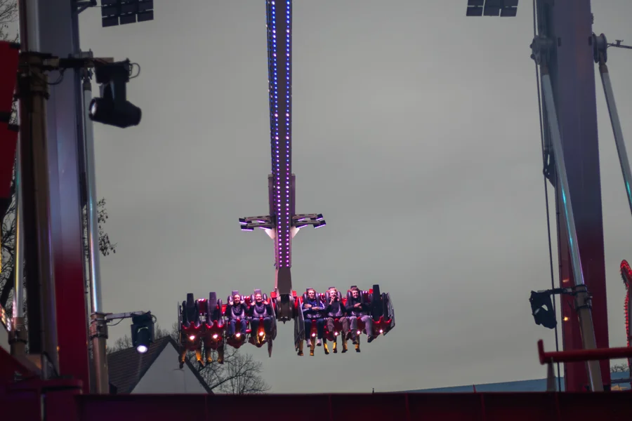 Violett beleuchteter Freifallturm neben Soester Kirchtürmen
